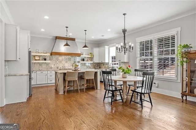 dining space featuring wood finished floors, ornamental molding, recessed lighting, a chandelier, and baseboards