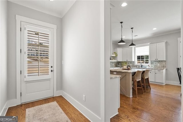 entryway featuring light wood-type flooring, a sink, baseboards, and recessed lighting