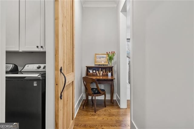 clothes washing area featuring cabinet space, ornamental molding, light wood-type flooring, washer and clothes dryer, and baseboards