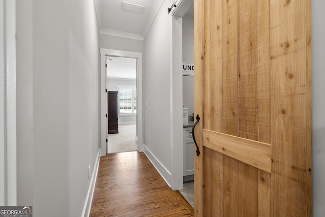 hallway with ornamental molding, wood finished floors, and baseboards