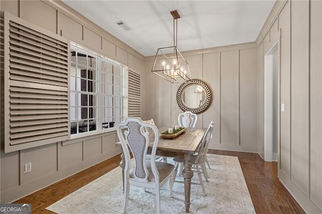 dining room with a decorative wall, a chandelier, and wood finished floors