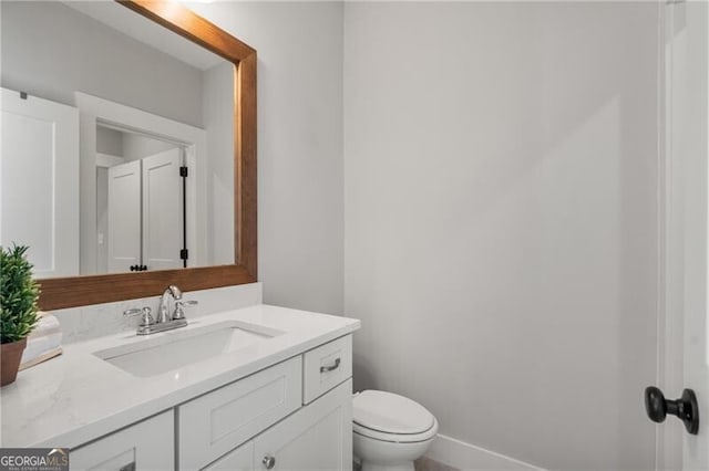 half bath featuring vanity and toilet