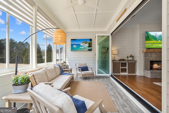 sunroom featuring an outdoor living space with a fireplace and ceiling fan