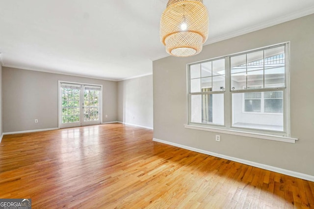 unfurnished room with baseboards, light wood-type flooring, a chandelier, and ornamental molding
