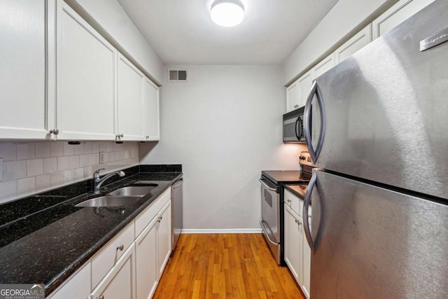 kitchen featuring visible vents, a sink, backsplash, stainless steel appliances, and light wood-style floors