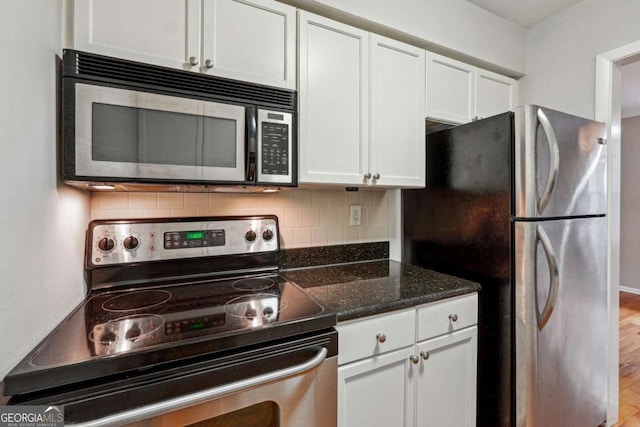 kitchen with decorative backsplash, dark stone counters, white cabinets, and appliances with stainless steel finishes