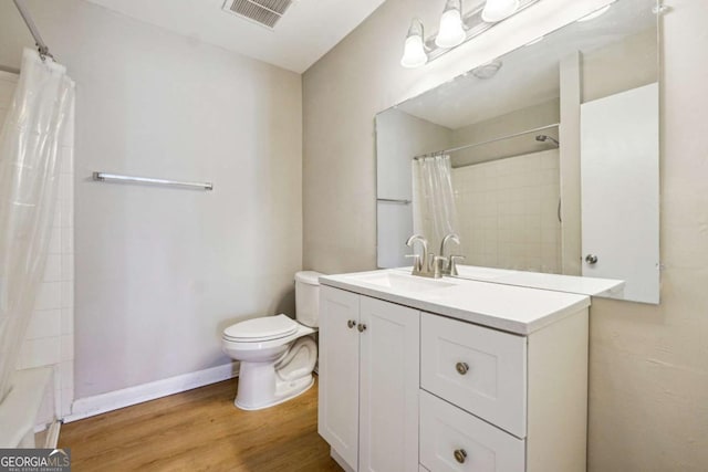 bathroom featuring vanity, wood finished floors, visible vents, baseboards, and toilet