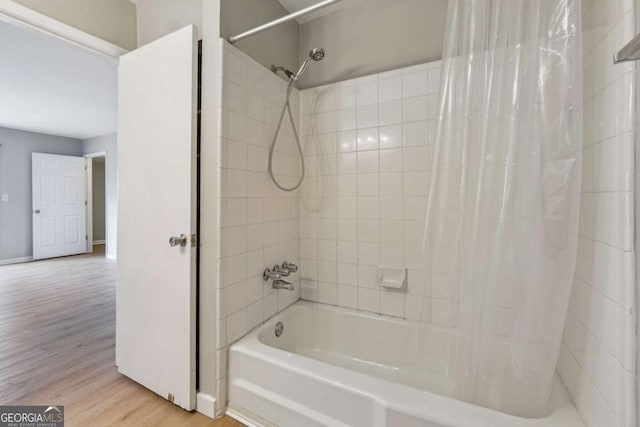 bathroom featuring shower / tub combo, wood finished floors, and baseboards