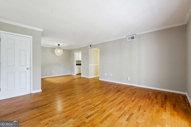 unfurnished living room featuring baseboards, visible vents, light wood finished floors, and ornamental molding