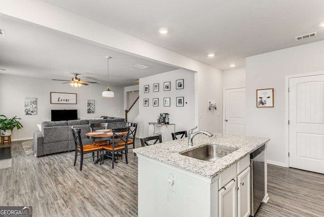 kitchen with visible vents, dishwasher, wood finished floors, a sink, and open floor plan