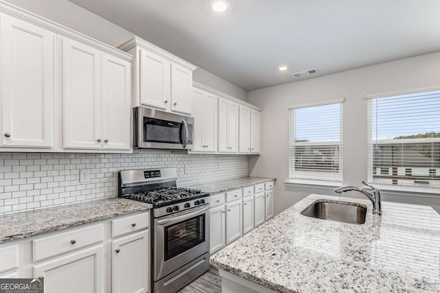 kitchen with visible vents, tasteful backsplash, appliances with stainless steel finishes, white cabinetry, and a sink