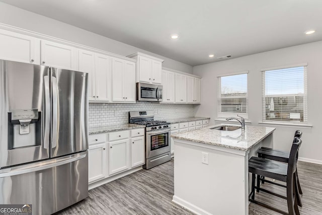 kitchen with a sink, white cabinets, appliances with stainless steel finishes, and tasteful backsplash