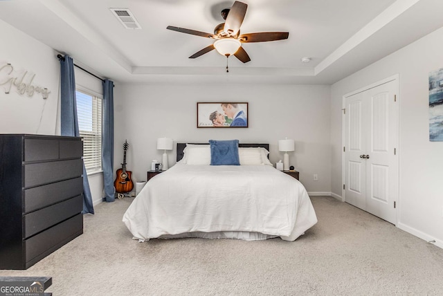 carpeted bedroom featuring a raised ceiling, baseboards, and visible vents