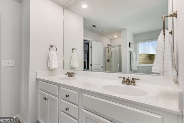 full bathroom with a stall shower, double vanity, visible vents, and a sink