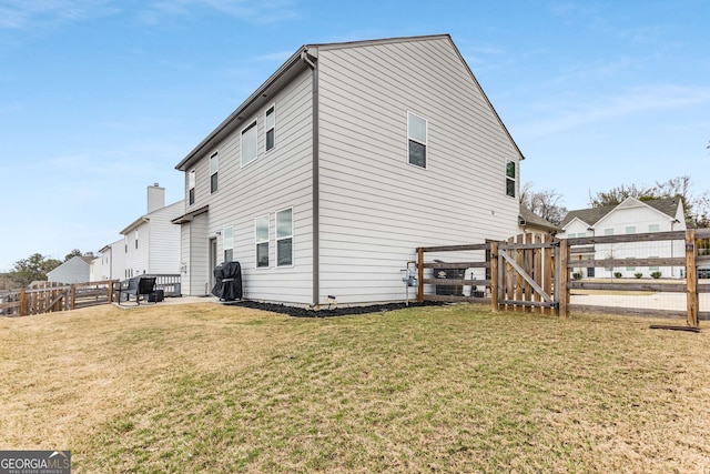 rear view of house featuring a gate, fence, and a yard