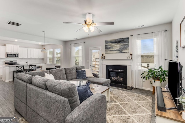 living room featuring light wood finished floors, a wealth of natural light, and visible vents