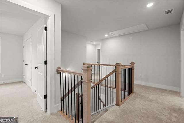 corridor featuring visible vents, an upstairs landing, carpet floors, and attic access