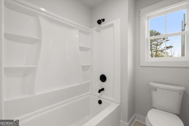 bathroom featuring toilet, bathing tub / shower combination, and baseboards