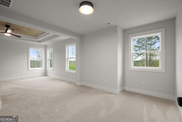 carpeted spare room with a tray ceiling, visible vents, and baseboards