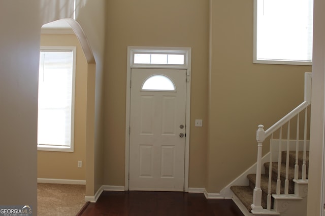 foyer entrance with stairway, baseboards, and a healthy amount of sunlight
