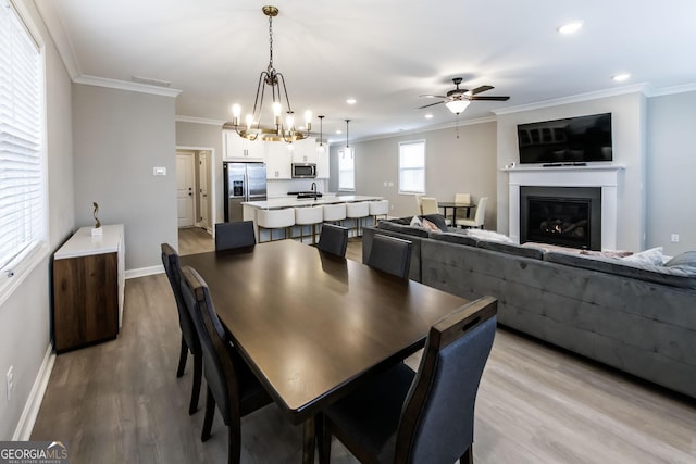 3739 Silvery Way, Powder Springs, GA 30127 - dining space with crown molding, ceiling fan with notable chandelier, baseboards, and light wood finished floors