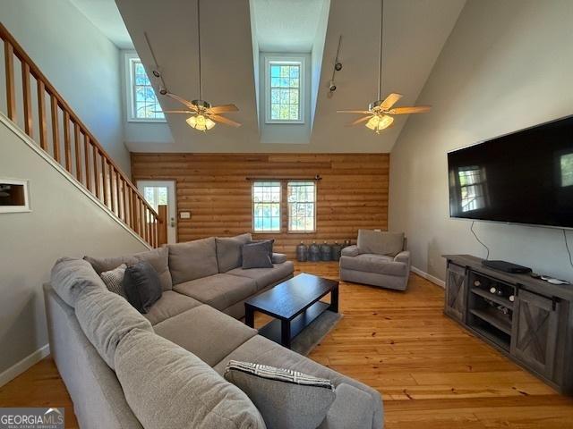living room featuring a wealth of natural light, stairway, light wood-type flooring, and ceiling fan