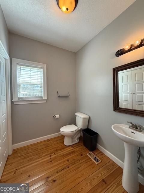 half bathroom featuring visible vents, baseboards, and wood finished floors
