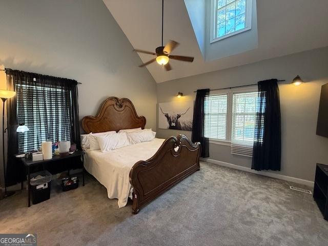 carpeted bedroom with high vaulted ceiling, baseboards, and a ceiling fan