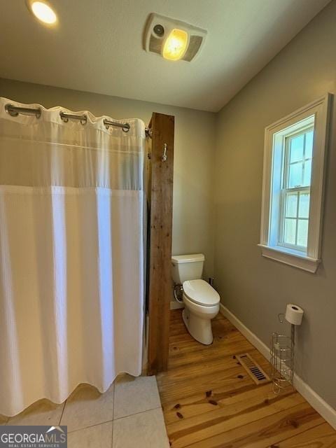 full bathroom with wood finished floors, visible vents, baseboards, curtained shower, and toilet