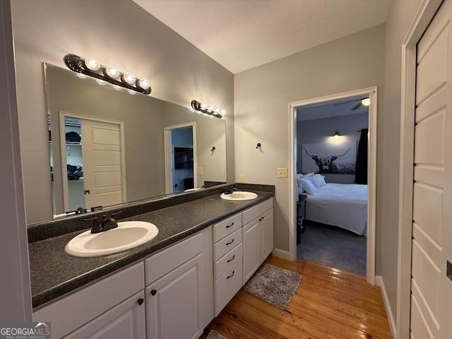 bathroom featuring a sink, connected bathroom, wood finished floors, and double vanity