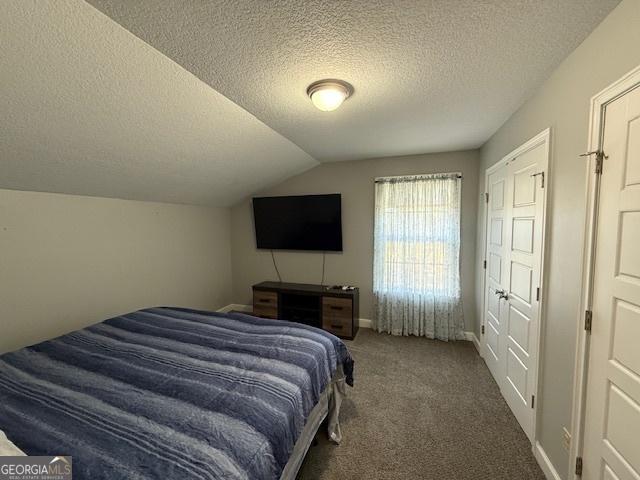 carpeted bedroom with lofted ceiling and a textured ceiling