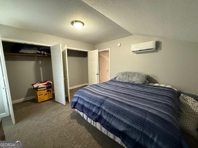 bedroom featuring baseboards, vaulted ceiling, carpet flooring, and a wall mounted AC