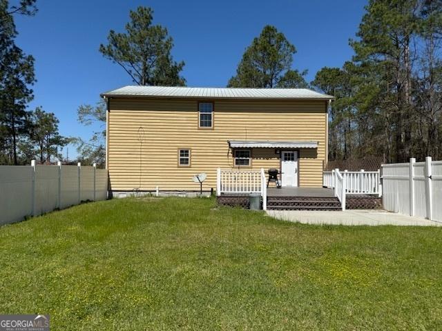 rear view of house with a lawn, a wooden deck, and a fenced backyard