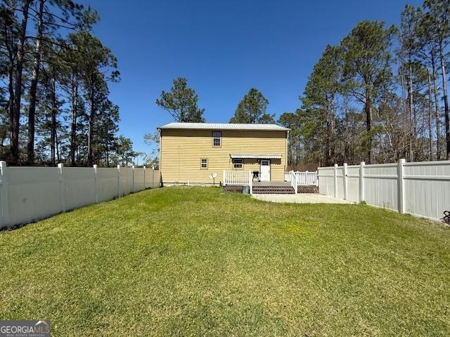 rear view of house featuring a lawn and a fenced backyard