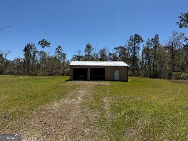 view of pole building featuring a lawn and dirt driveway