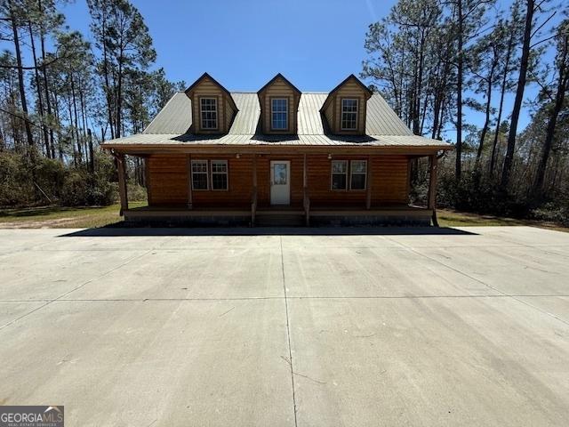 chalet / cabin featuring faux log siding, covered porch, and metal roof