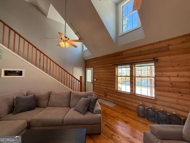 living room featuring a high ceiling, stairs, ceiling fan, and hardwood / wood-style floors
