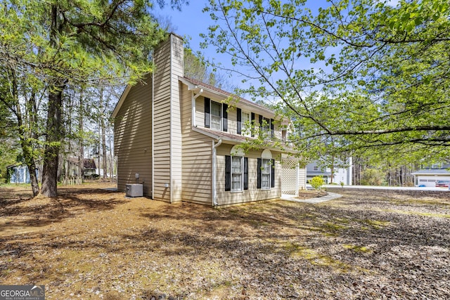 view of home's exterior featuring cooling unit and a chimney