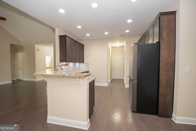 39 Chatham Ct, Williamson, GA 30292 - kitchen featuring a peninsula, a kitchen breakfast bar, baseboards, freestanding refrigerator, and light stone counters