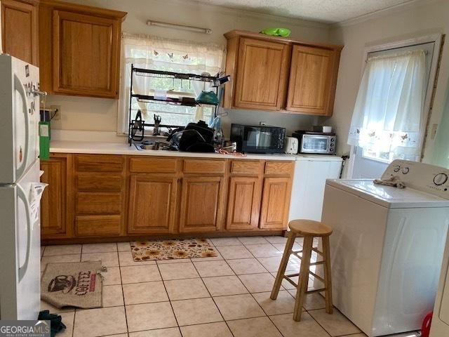 kitchen featuring washer / clothes dryer, brown cabinets, and black microwave