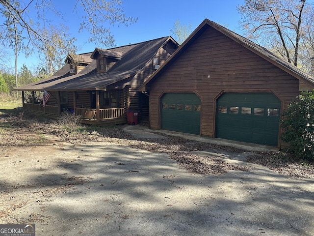 view of side of property featuring a porch, an attached garage, and driveway