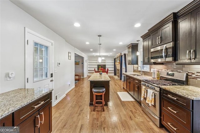 kitchen featuring backsplash, a center island, light stone countertops, light wood-style floors, and stainless steel appliances