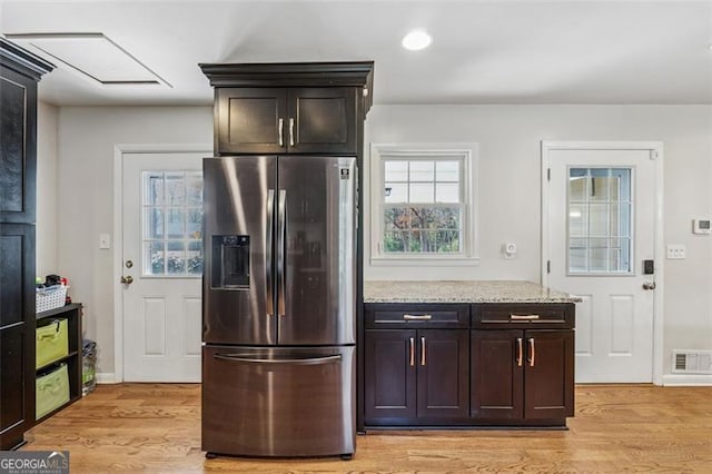 kitchen featuring light wood-style floors, stainless steel fridge with ice dispenser, visible vents, and light stone countertops