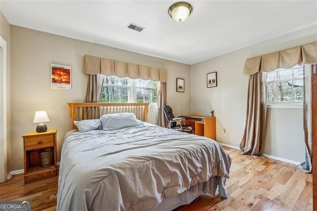 bedroom featuring light wood-type flooring, visible vents, and baseboards