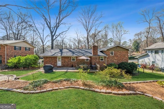 rear view of property with brick siding, a patio, a chimney, and a yard