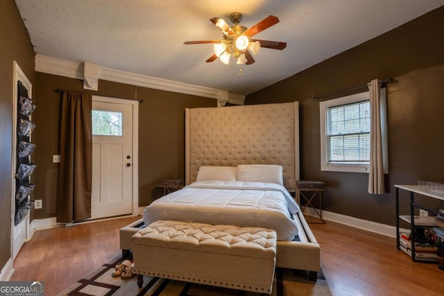bedroom with lofted ceiling, ornamental molding, wood finished floors, baseboards, and ceiling fan