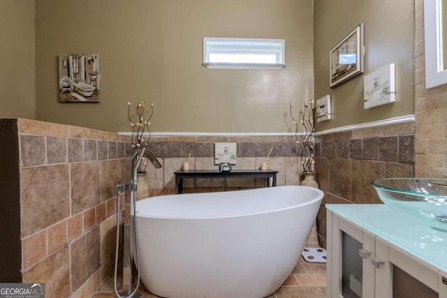 full bath with vanity, tile walls, a wainscoted wall, and a freestanding bath