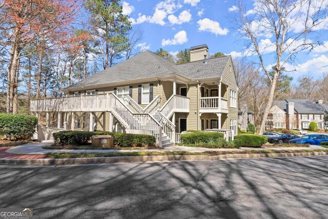 exterior space featuring stairway, a chimney, and a shingled roof