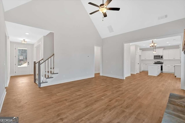 unfurnished living room featuring visible vents, stairs, light wood-style flooring, high vaulted ceiling, and a ceiling fan