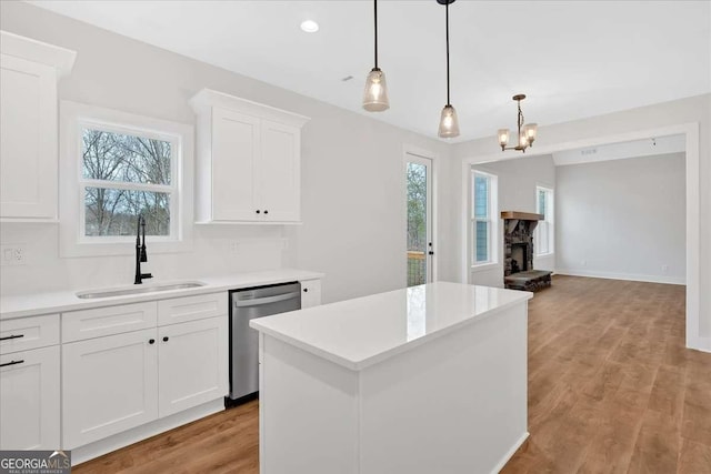 kitchen featuring a wealth of natural light, a sink, a kitchen island, and stainless steel dishwasher